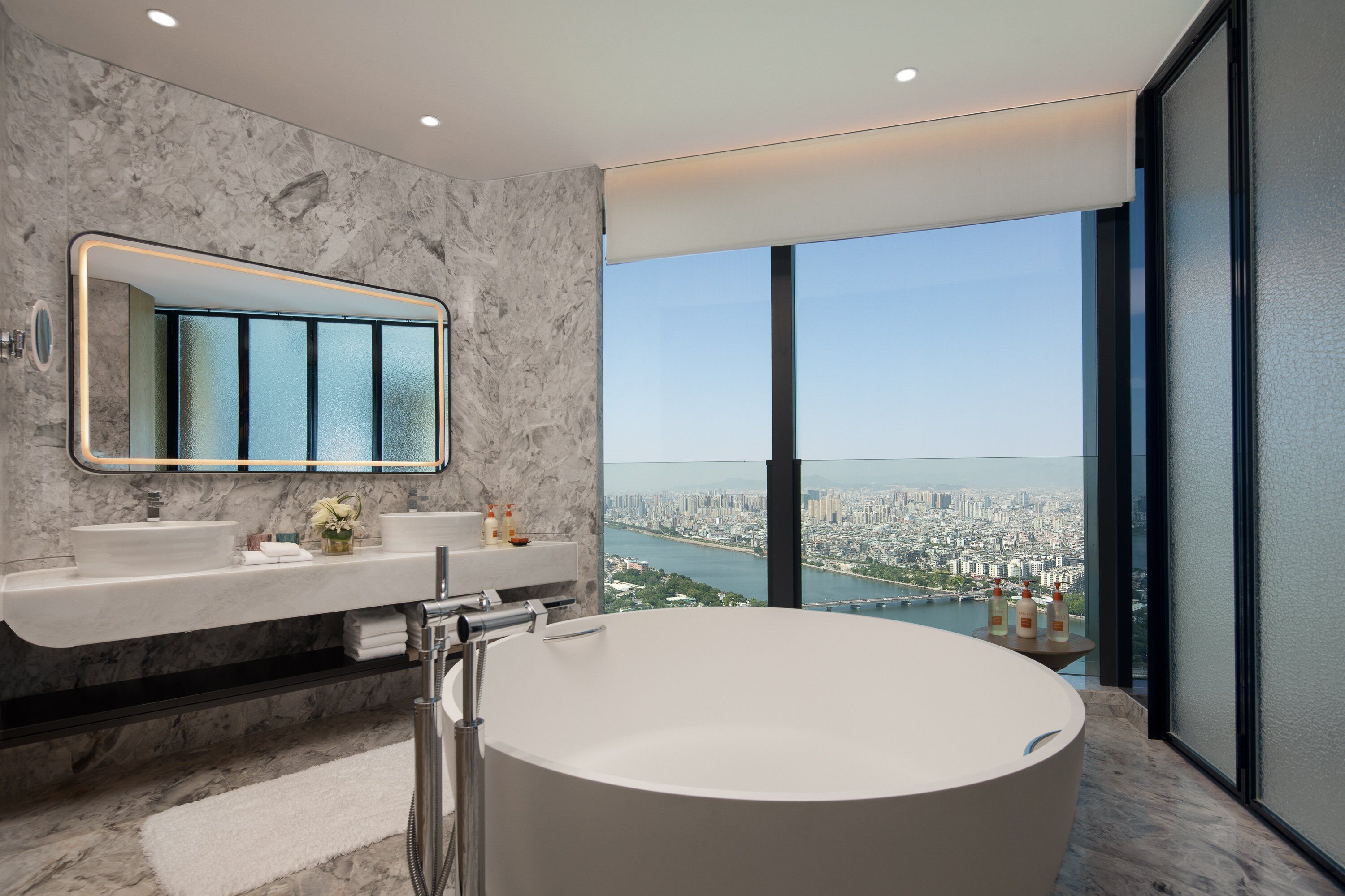 A modern bathroom with a large bathtub, a dual sink vanity, and a large mirror.