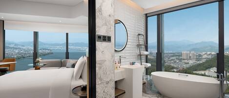 Un baño moderno con una bañera grande, un espejo redondo y vistas a la ciudad.