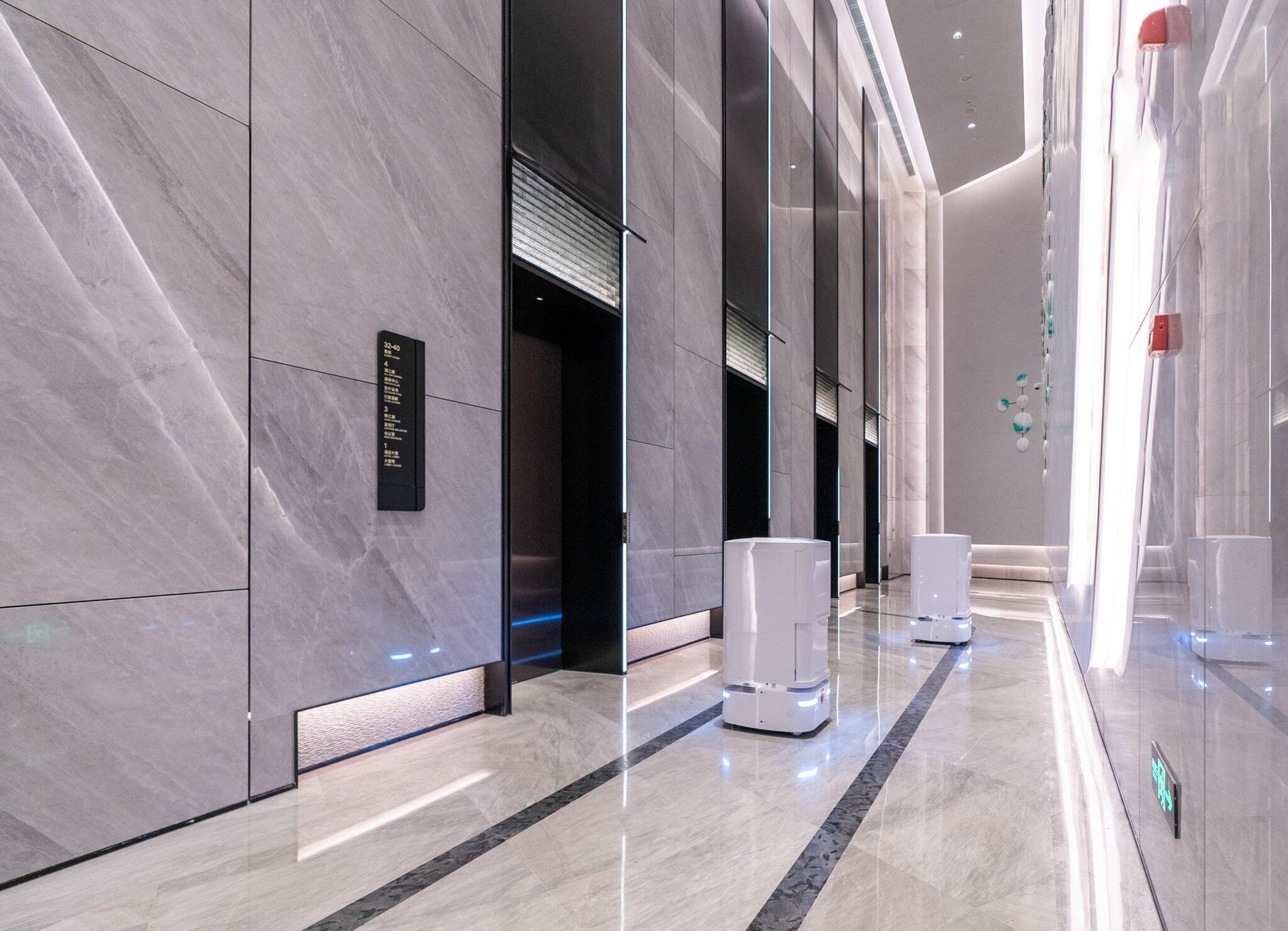 A modern hallway with a marble floor, a directional sign, and a row of white cylindrical objects.