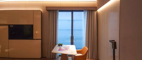 A hotel room with a bed, a desk with a chair, a television, and a window with curtains.