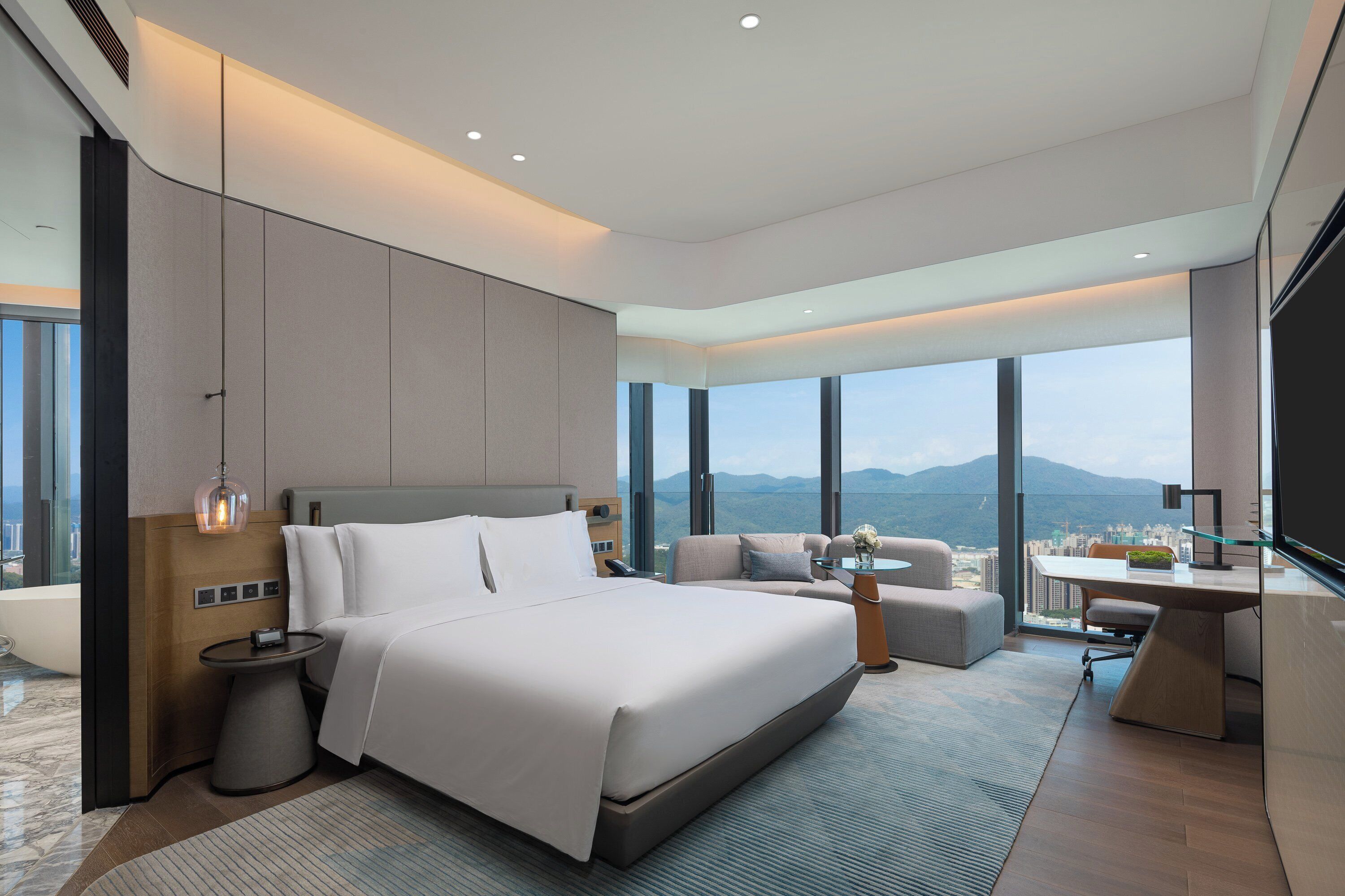 Una habitación de hotel moderna con una cama grande, un escritorio y vistas a la ciudad.