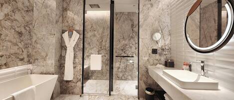A modern bathroom with a bathtub, a large mirror, and marble walls.