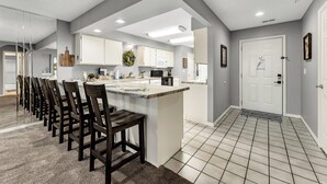 A modern kitchen with a central island, dark wooden chairs, and a tiled floor. - Fantastic Location! Indoor and Outdoor Pools, Hot tub, Golf & Shows! (Branson)