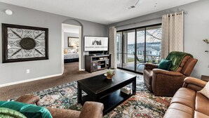 A modern living room with a dark wooden coffee table, leather sofas, and a large window offering a view of the outdoors. - Fantastic Location! Indoor and Outdoor Pools, Hot tub, Golf & Shows! (Branson)