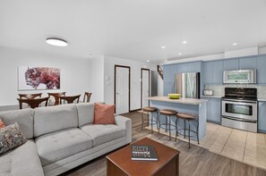 A modern apartment with a living room, dining area, and kitchen. - Borealis Homes (Mont-Tremblant)