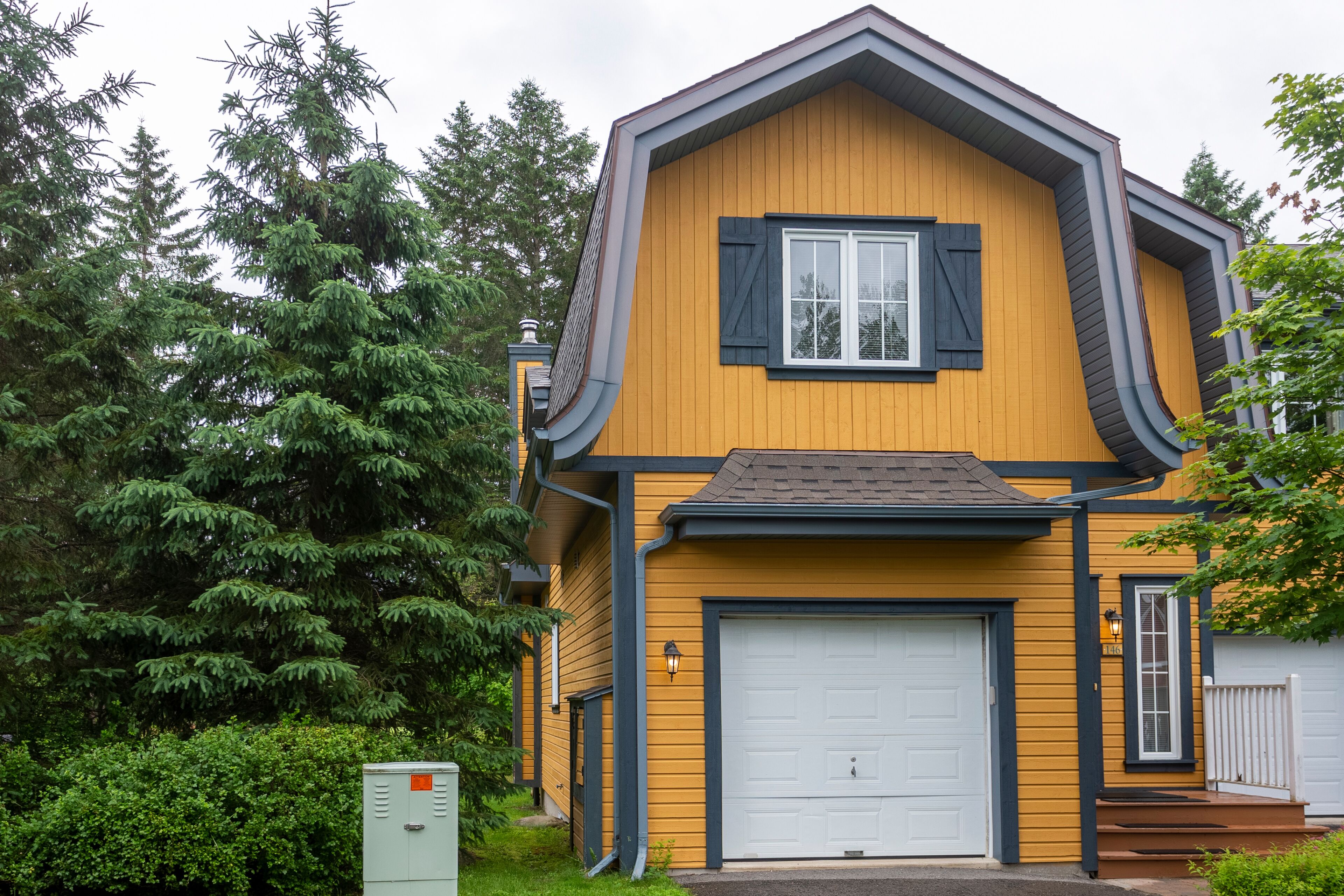 A two-story house with a garage, surrounded by trees.