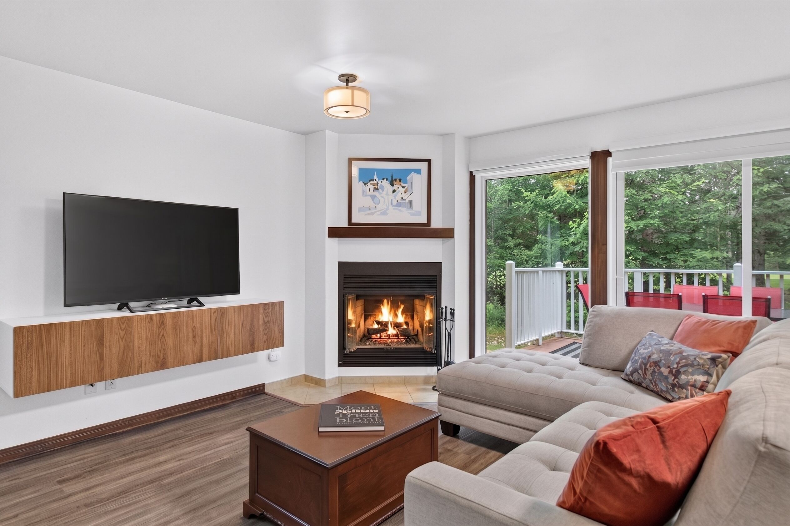 A living room with a flat-screen TV, a fireplace, a sofa, and a view of a deck.