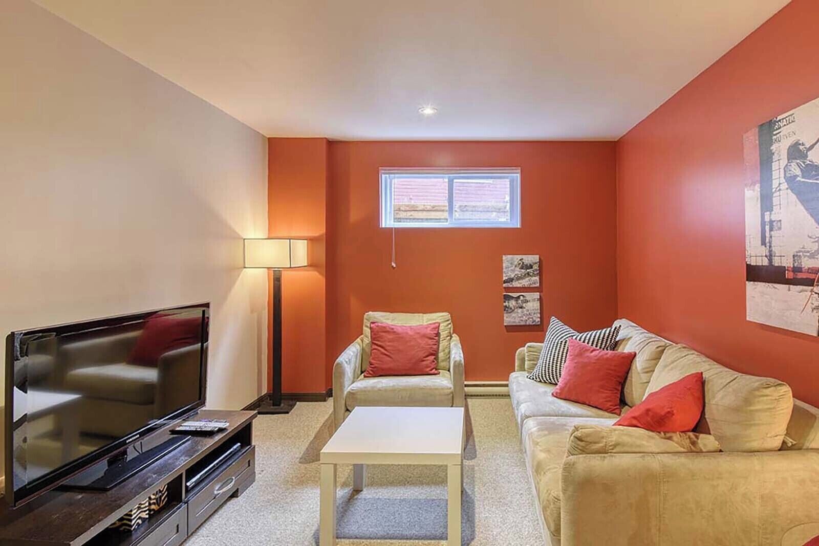 Un salon équipé d’un téléviseur à écran plat, de deux fauteuils, d’un canapé, d’une petite table et d’un lampadaire.