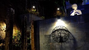 A stone wall with a metal tree sculpture illuminated by a spotlight. - Veiga da Fraga, all the secrets of Galicia and the Rías Baixas (PONTEVEDDRA, POIO)