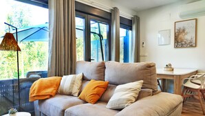 A modern living room with a beige sofa, a small round table, and a dining area with a wooden table and chairs. - Veiga da Fraga, all the secrets of Galicia and the Rías Baixas (PONTEVEDDRA, POIO)