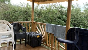 Um deck de madeira coberto com móveis de exterior, churrasqueira e um depósito.