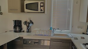 Uma cozinha moderna com micro-ondas integrado, cafeteira e pia.