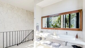 A modern bathroom with a large mirror, two sinks, and a staircase with a railing. - Villa LaGú • Luxury 5BR Jungle Villa • Pool, Spa & Chef (Tulum)
