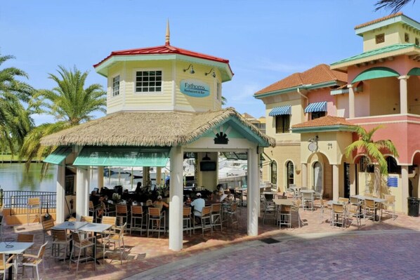 Un restaurant appelé « Fathoms », doté d’une terrasse et d’une structure avec un toit de chaume.