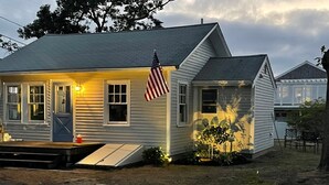 Una casa a un piano con veranda, una bandiera americana e un piccolo giardino.