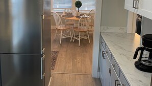 Una cucina moderna con un frigorifero in acciaio inox, un'area pranzo con un tavolo e sedie in legno e una macchina da caffè sul bancone.