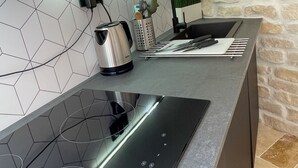 A modern kitchen with a black induction cooktop, a kettle, and a knife block. - Renovated apartment for 3 in the heart of old Antibes (Antibes)