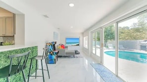 Une cuisine moderne avec un bar, un coin salon offrant une vue sur l’océan et une piscine.