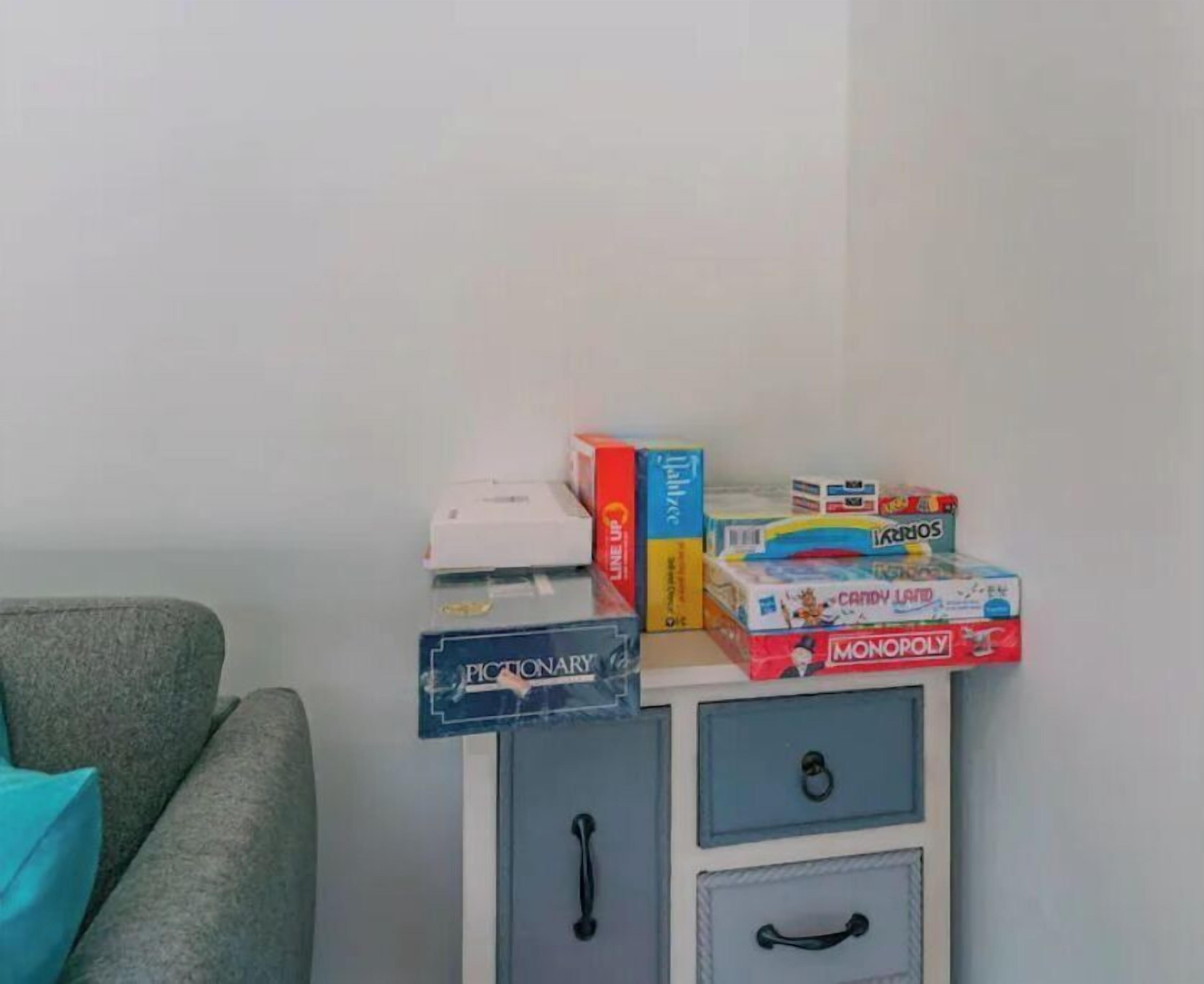 Une petite table sur laquelle sont disposés divers jeux de société et une boîte blanche.