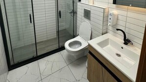 Une salle de bain moderne avec une douche à parois de verre, des toilettes blanches et un lavabo avec un miroir au-dessus.
