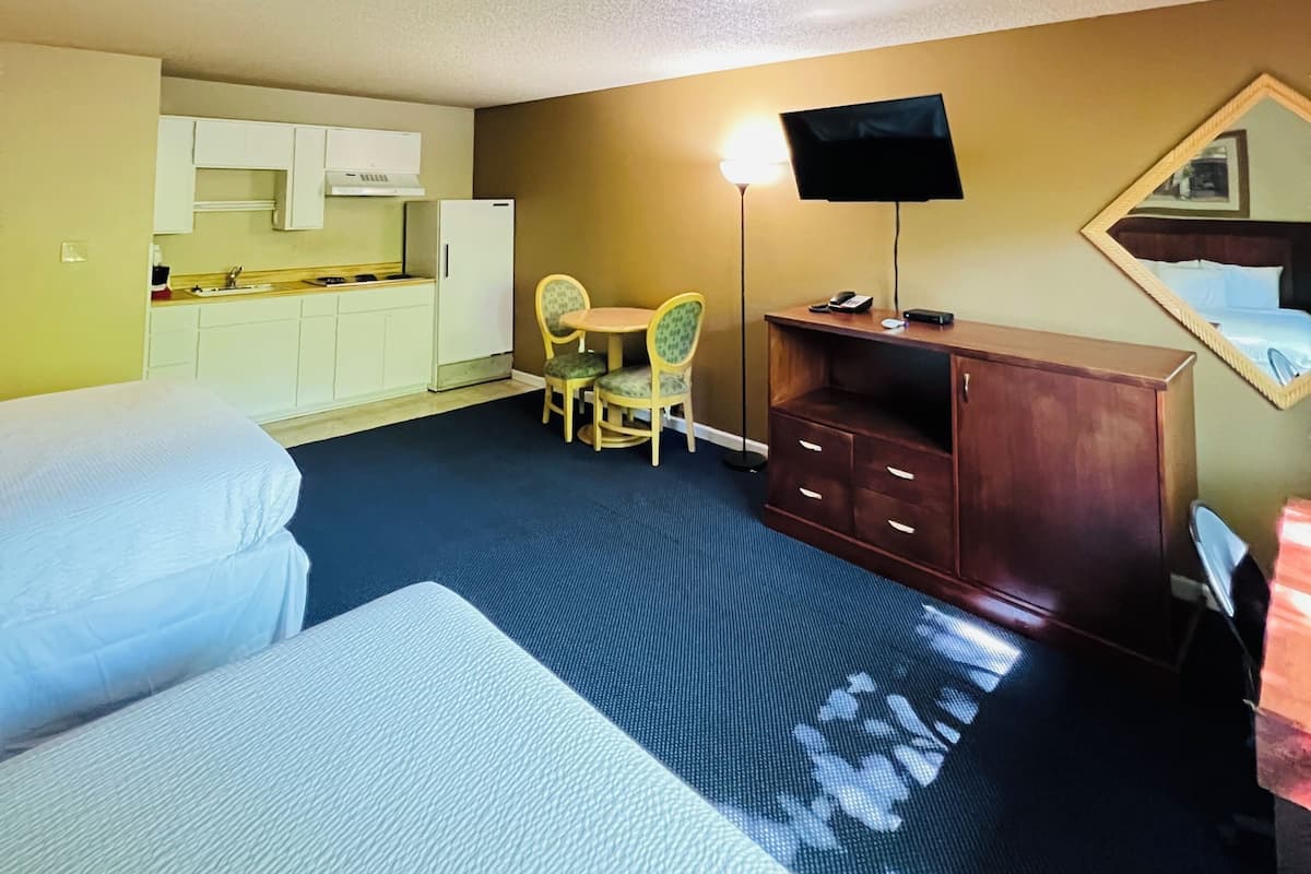 A hotel room with a bed, a desk, a chair, a television, and a mirror.