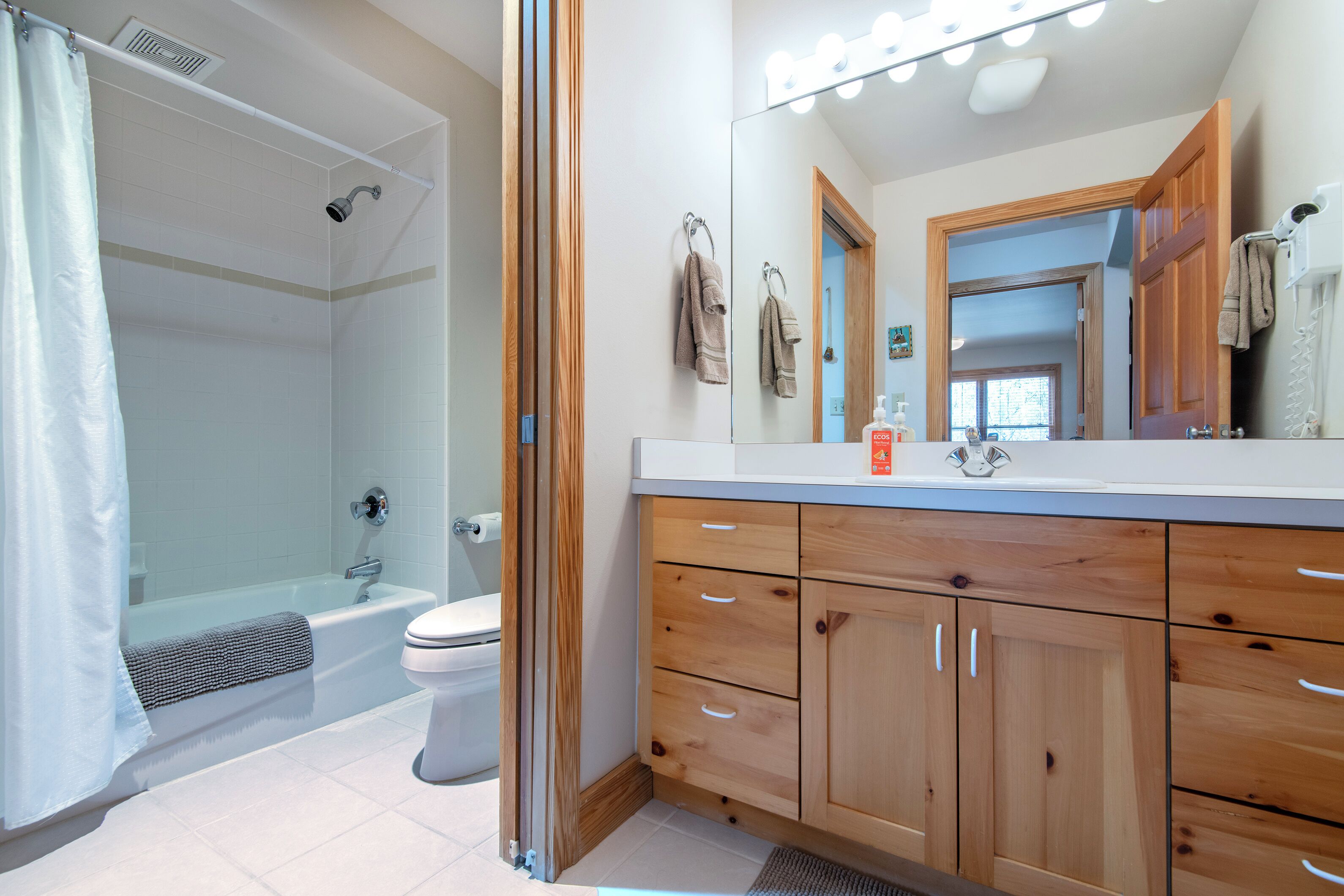 A bathroom with a shower, toilet, and wooden cabinets.