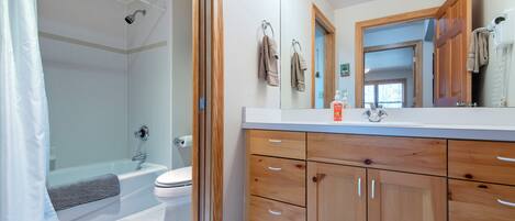 A bathroom with a shower, toilet, and wooden cabinets.