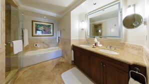 A spacious bathroom with a large bathtub, two sinks, and a glass-enclosed shower area.