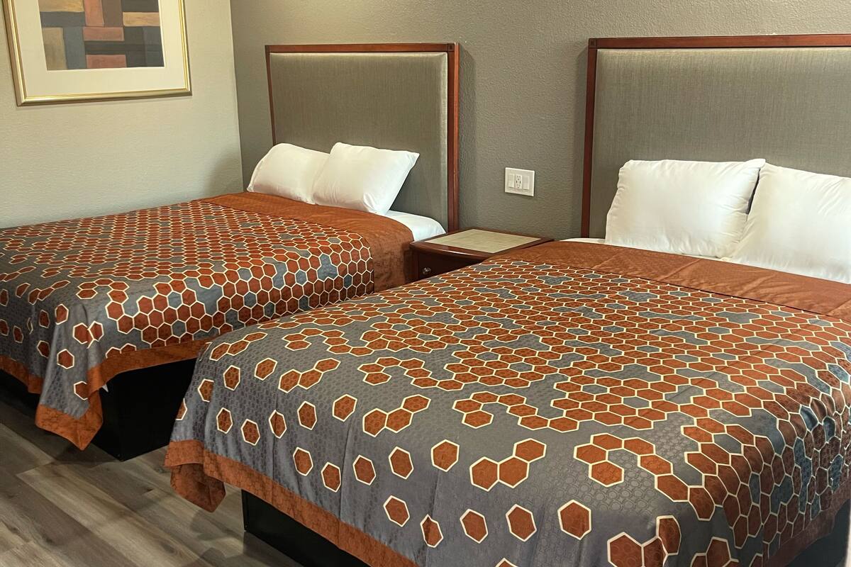 A hotel room with two beds, each with a patterned bedspread and headboard.