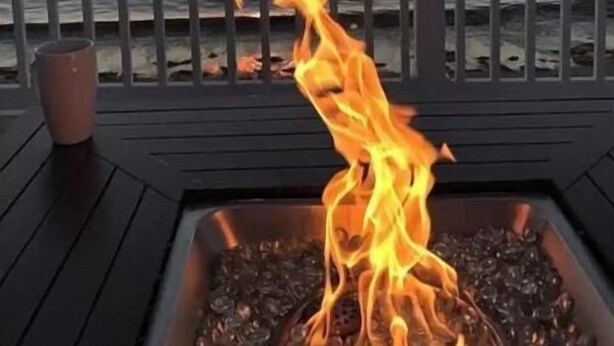 A deck with a fire feature and a view of the sunset over the ocean.