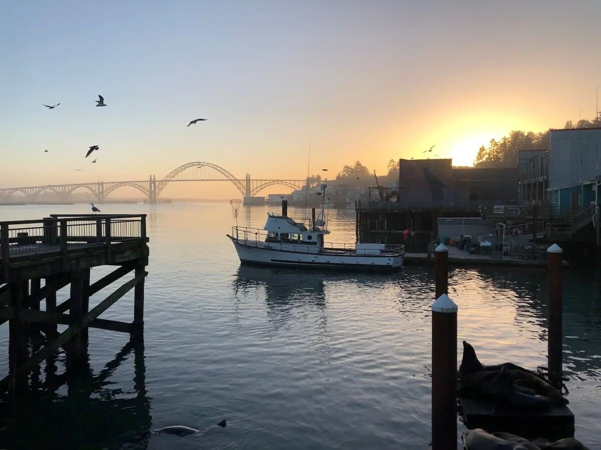 A waterfront scene with a bridge, a dock, and a boat.