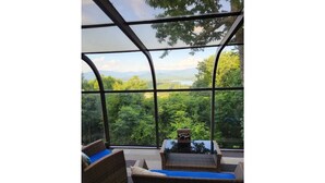 Une véranda meublée de mobilier en osier, offrant une vue sur un paysage luxuriant.