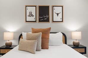 Bedroom setup with custom desert playing card art over the bed and matching bedside tables.