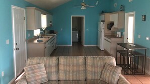 A compact living space with a kitchenette, a sofa, and a ceiling fan. - Peaceful bungalow and birdwatcher's paradise 1/2 mile to the Gulf beach. (Gulf Shores)
