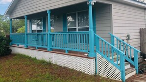 A house with a porch, a staircase, and a fenced yard. - Peaceful bungalow and birdwatcher's paradise 1/2 mile to the Gulf beach. (Gulf Shores)