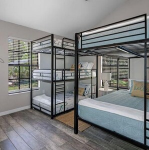 Cozy room with a bunk bed setup, featuring a window with blinds and a patterned carpet.