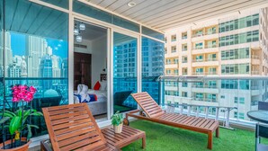 A balcony with wooden loungers, a small table, and a potted plant. - ZAPBED House OPT 701&34 (Dubai)