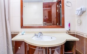 Casa de banho com lavatório, espelho, porta-toalhas e secador de cabelo.