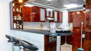 A modern kitchen with wooden cabinets, a bar area with stools, and a stainless steel countertop. - ZAPBED House OPT 701&34 (Dubai)
