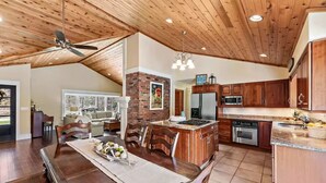 A spacious kitchen with wooden cabinets, a built-in island, and a dining area with a large wooden table. - Perfect retreat for multi-generational families! Sat-Saturday lakeside rental. (Three Oaks)