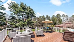 A wooden deck with outdoor furniture, including sofas and a dining table, surrounded by a white fence. - Perfect retreat for multi-generational families! Sat-Saturday lakeside rental. (Three Oaks)