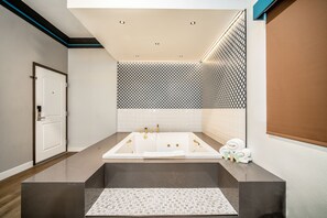 Une salle de bain moderne avec une grande baignoire, un miroir et un porte-serviettes.