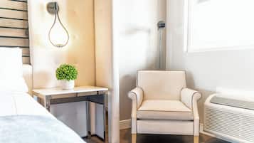 Une chambre d’hôtel moderne équipée d’un lit, d’un petit bureau avec une plante, d’une chaise et d’un radiateur portatif.