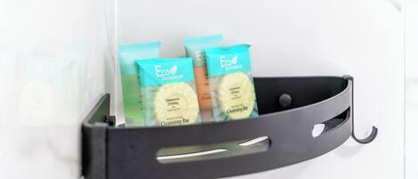 A black metal shelf with three Eco Botanics cleansing bars in a bathroom setting.