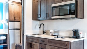 A modern kitchen with wooden cabinets, stainless steel appliances, and a white countertop. - Aspire Inn Studios & Spas (Bellflower)