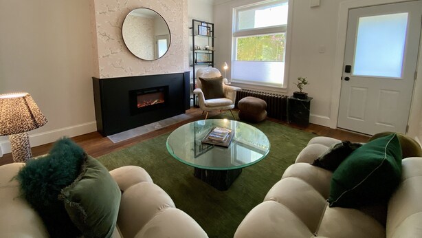A living room with a fireplace, a round mirror, a glass coffee table, and a comfortable seating area. - Peaceful full home in the heart of Southside Flats. (Pittsburgh)