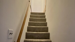 A carpeted staircase with a wooden handrail and a light fixture at the top. - Peaceful full home in the heart of Southside Flats. (Pittsburgh)