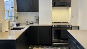 A modern kitchen with black cabinets, a stainless steel oven, and a microwave. - Peaceful full home in the heart of Southside Flats. (Pittsburgh)