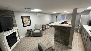 A modern living room with a fireplace, a television, a gray sofa, and a dining area with a table and chairs.