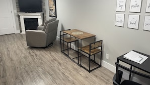 A modern living room with a fireplace, a sofa, a dining table, and motivational wall art.